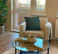Living room of a two-room apartment with an armchair and a coffee table, floor with wooden decor.