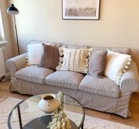 A bright living room in a 2-room apartment with a sofa, a table, and decorative pillows.