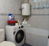 A bathroom in a family house with a shower, a washing machine, and a gas boiler.
