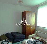 A room in a family house with furniture and a large window provides comfortable seating.