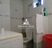 Bathroom in a family house with a washing machine, toilet, and cleaning products.