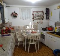 A kitchen in a family house with simple furnishings, floral decorations, and a gas stove.