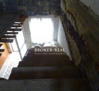 A staircase in the interior of a family house with a stone wall and wooden elements.
