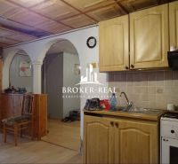 A kitchen with an arched doorway, wooden cabinets, a floor with a wooden design, family house.