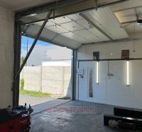 Garage in Gardens with open gates, view of the paved area.