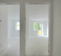 A white interior of an empty 2-room apartment with a window and balcony doors.