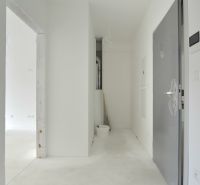 A hallway in a 2-room apartment with a concrete floor and open doors.