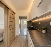 A kitchen in a 2-room apartment with a wooden decor floor and sliding doors.