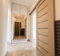 A hallway with tiles, sliding doors, and a mirrored wardrobe in a 2-room apartment.