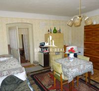 A room in a family house with a tiled stove and a carpet on the floor with a wooden decor.