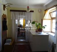 An old hallway of a family house with plants and curtains on the windows.