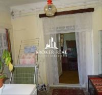 Interior of a family house with a lace curtain, a plant, and a clothes drying rack.