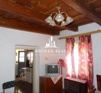 Interior of a family house with a wooden ceiling, television, and colorful curtains.