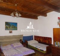 A room in a family house with a wooden ceiling, two beds, and a cabinet with decorations.