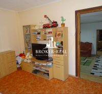 A room with a storage wall, a television, and open doors in a family house.