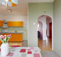A kitchen in a family house with orange cabinets and flowers on the table.