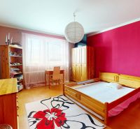 Bedroom in a family house with a bed, cabinet, and desk, floor with wooden decor.
