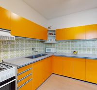 An orange kitchen in a family house with a gas stove and green tiles.