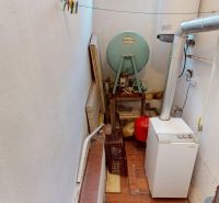 Boiler room in a family house with an old boiler, pipes, and storage space.