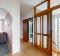 Interior of a family house with a wooden decor floor, a sofa, and glass doors.