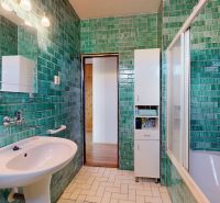 Bathroom in a family house with turquoise tiles and a bathtub.