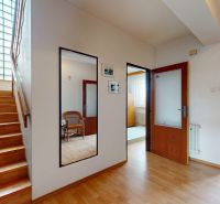 Interior of a family house with a wood-patterned floor, staircase, and glass doors.