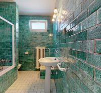 Bathroom in a family house with turquoise tiles and a white sink.