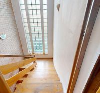 Wooden staircase and glass wall in a family house with brick decor.