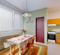 A kitchen in a family house with a retro kitchen unit, a dining table, and floral decorations.