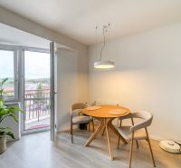 Dining area with a round table in a 3-room apartment, floor with wooden decor.