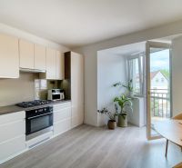A kitchen in a 3-room apartment with a wooden decor floor and balcony doors.