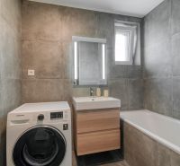 Bathroom in a 3-room apartment with a bathtub, sink, and washing machine on tiles.