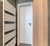 A bathroom in a 3-room apartment with a ladder radiator and a wooden cabinet.