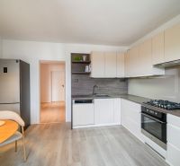 A kitchen with a wooden decor floor, a dining table, and modern appliances in a 3-room apartment.