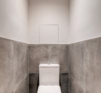 A toilet with a ceramic surface and bright lighting in a 3-room apartment.