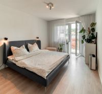 A bedroom in a 3-room apartment with a bed, balcony doors, and decorative plants.