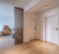A hallway with a wooden decor floor and an entrance to the living room in a three-room apartment.
