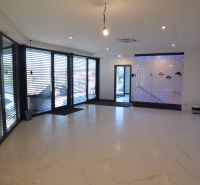 Interior with large windows, white tiles, and a floor with a wooden design.