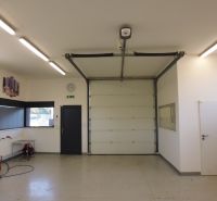 Interior of warehouses and halls with white walls, a garage door, and lighting.