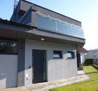 A modern house with a terrace and glass in Kračúnovce, surrounded by green grass.