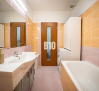 Bathroom in a 2-room apartment with light tiles, a bathtub, and a washing machine.