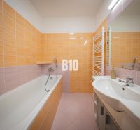 A bathroom in a 2-room apartment with a bathtub and orange tiles.