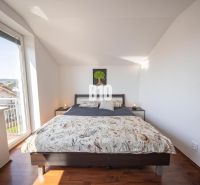 A bright bedroom with a large bed and a wooden decor floor in a 2-room apartment.