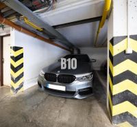 A garage parking space for a car with striped pillars and pipes on the ceiling.