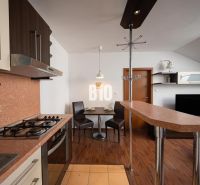 A kitchen with a bar counter and a wooden decor floor in a 2-room apartment.