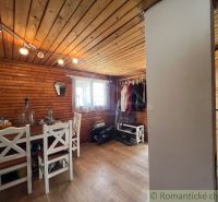 The interior of a cabin with wooden paneling, a table and chairs, and a floor with a wooden decor.