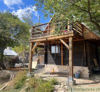 A cottage in Bratislava IV surrounded by trees, wooden balcony, summer day.