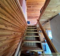 Wooden stairs leading to the attic in a cabin with wooden decor.
