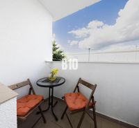A balcony of a 3-room apartment with seating, a view of the sky, and flowers in Bratislava IV.
