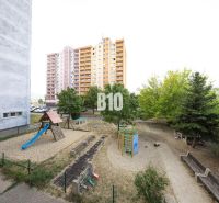 A children's playground in Bratislava IV near a panel building, a 3-room apartment in the background.